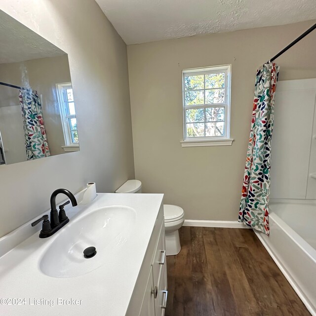 full bathroom featuring toilet, a textured ceiling, hardwood / wood-style flooring, vanity, and shower / bath combination with curtain