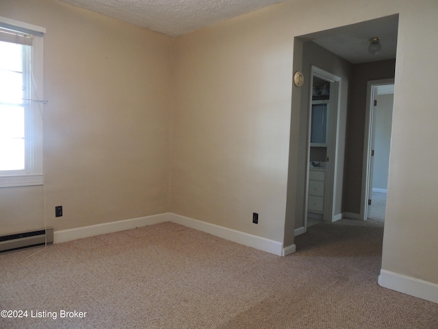 empty room with plenty of natural light, carpet, a baseboard radiator, and a textured ceiling