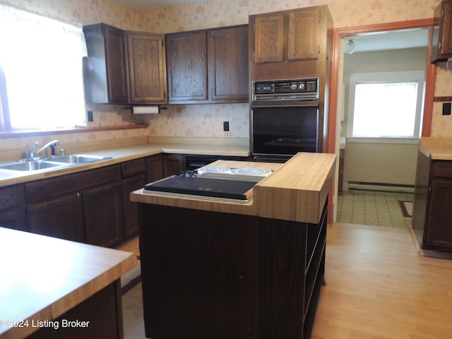 kitchen with dark brown cabinets, a kitchen island, a baseboard heating unit, sink, and oven