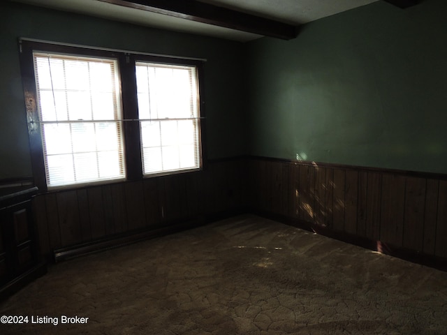 empty room with beamed ceiling, carpet floors, and wooden walls