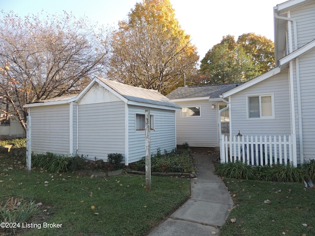 view of property exterior featuring a lawn and an outdoor structure