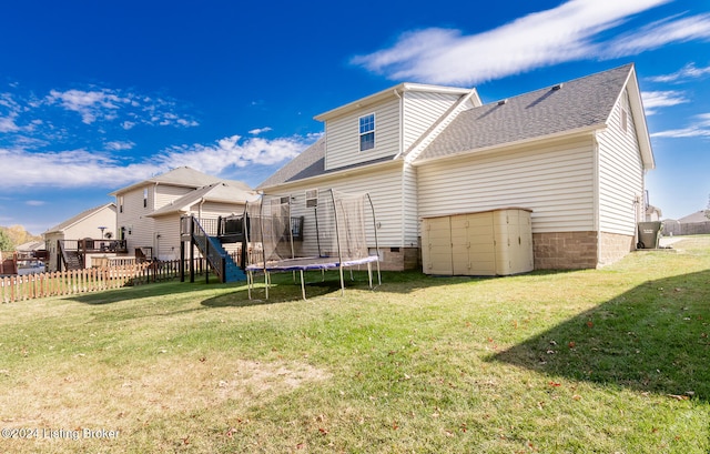 back of house featuring a yard and a trampoline