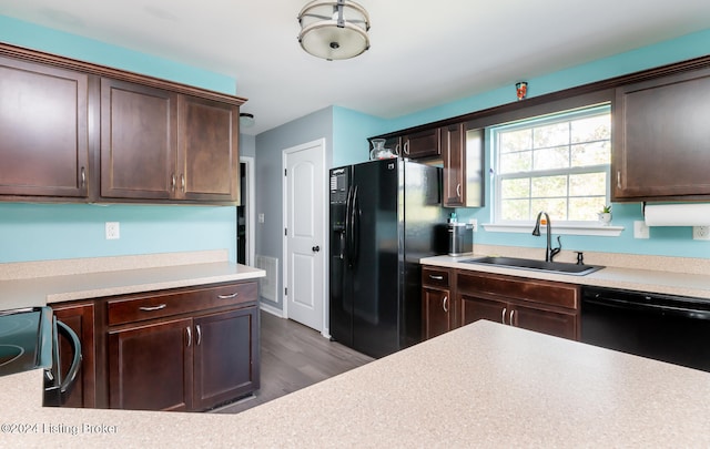 kitchen featuring dark brown cabinetry, dark hardwood / wood-style floors, black appliances, and sink