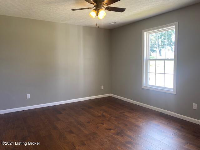 empty room featuring a textured ceiling, dark hardwood / wood-style floors, and ceiling fan