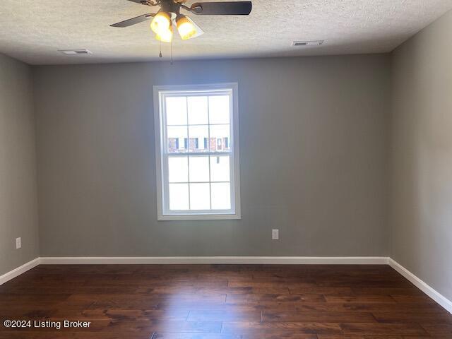 unfurnished room with ceiling fan, a textured ceiling, and dark hardwood / wood-style floors