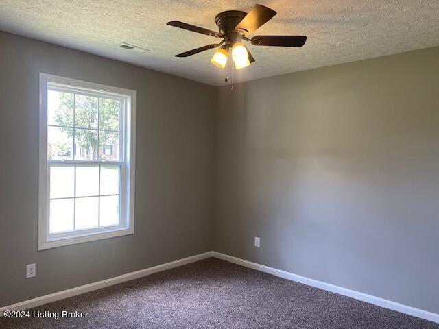 spare room featuring a textured ceiling, carpet flooring, and ceiling fan