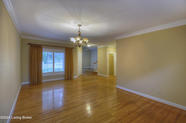 empty room with hardwood / wood-style floors, a chandelier, and ornamental molding