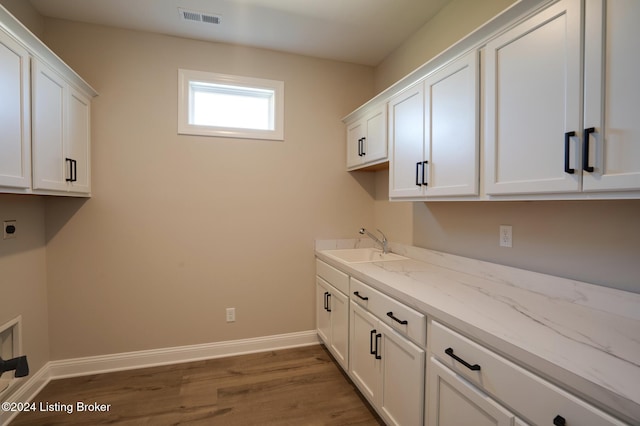 laundry area with sink, hookup for an electric dryer, cabinets, and dark wood-type flooring