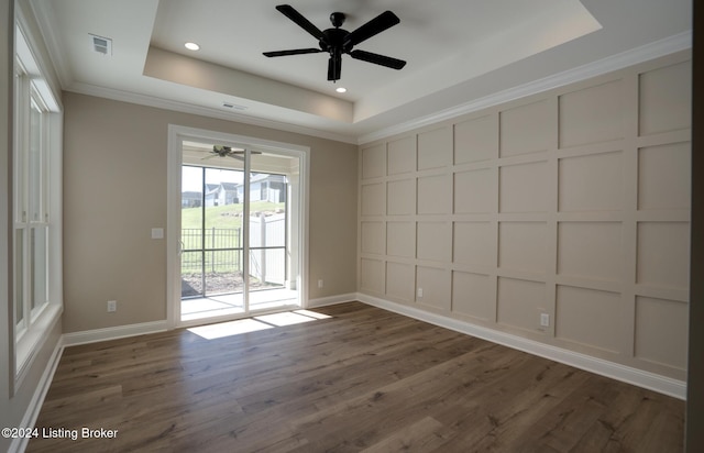 spare room with a raised ceiling, crown molding, dark hardwood / wood-style flooring, and ceiling fan