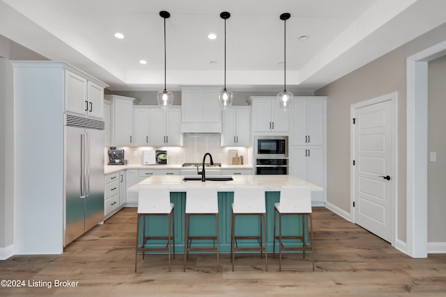 kitchen with built in appliances, pendant lighting, and white cabinetry