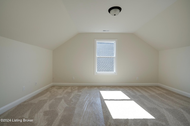 additional living space featuring light carpet and vaulted ceiling