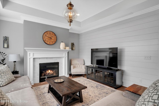 living room featuring crown molding, a raised ceiling, and wood walls