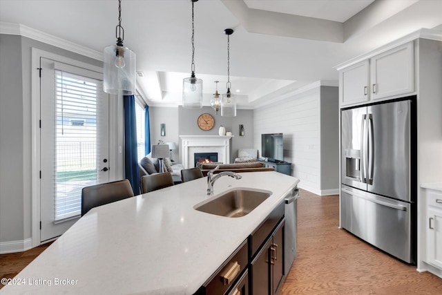 kitchen featuring hanging light fixtures, a raised ceiling, white cabinetry, sink, and stainless steel appliances