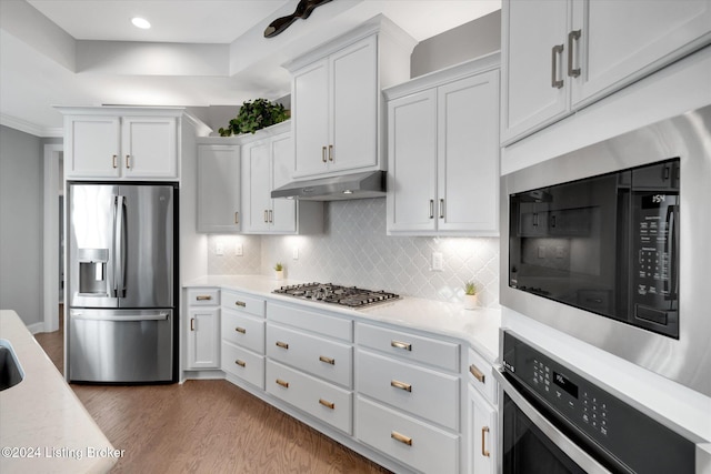 kitchen with stainless steel appliances, tasteful backsplash, light hardwood / wood-style flooring, and white cabinets