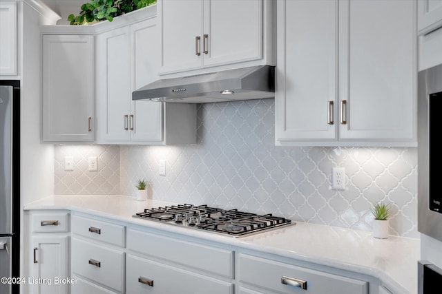 kitchen featuring white cabinets, stainless steel appliances, ventilation hood, and backsplash