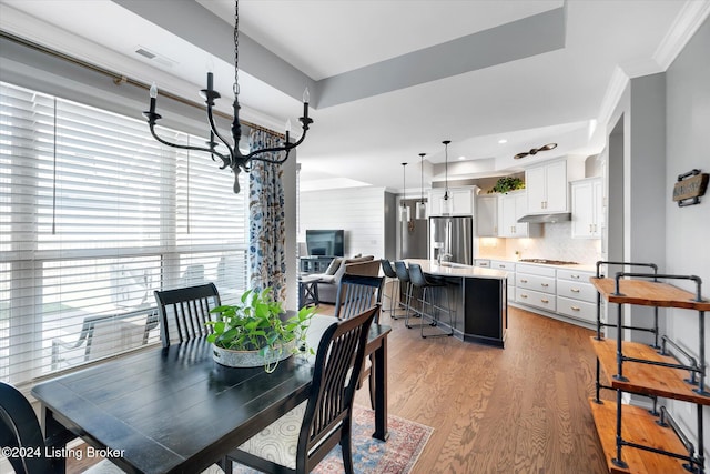 dining room featuring light hardwood / wood-style flooring, a notable chandelier, and crown molding