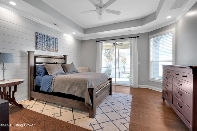 bedroom featuring wood walls, access to outside, light wood-type flooring, a tray ceiling, and ceiling fan