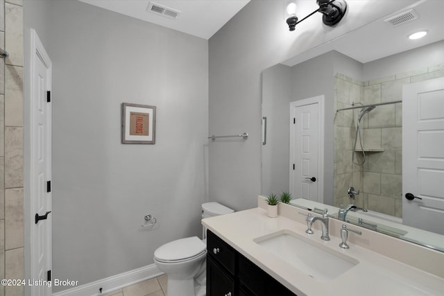 bathroom featuring vanity, a tile shower, toilet, and tile patterned floors