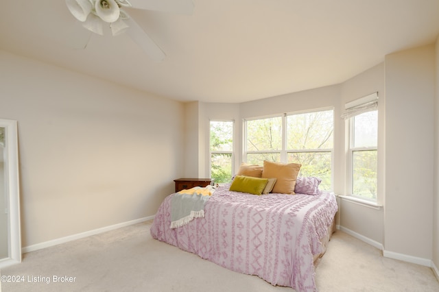 bedroom with light colored carpet, multiple windows, and ceiling fan