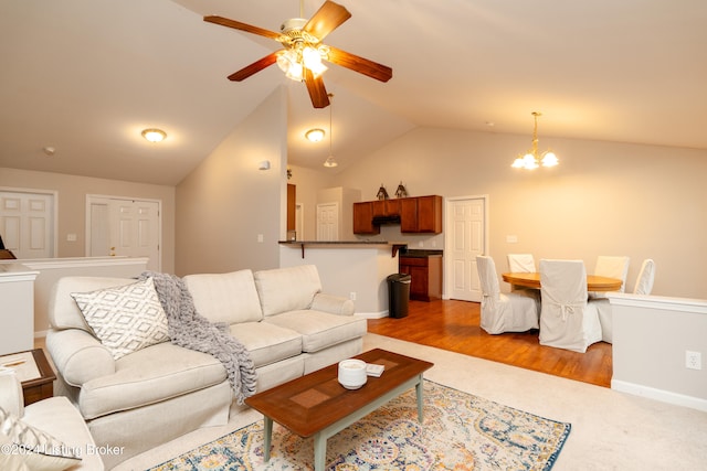 living room featuring ceiling fan with notable chandelier, light hardwood / wood-style floors, and vaulted ceiling