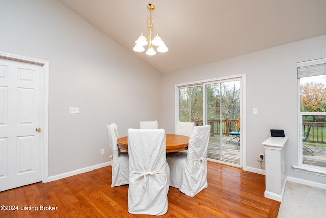 dining space featuring hardwood / wood-style flooring, vaulted ceiling, and an inviting chandelier