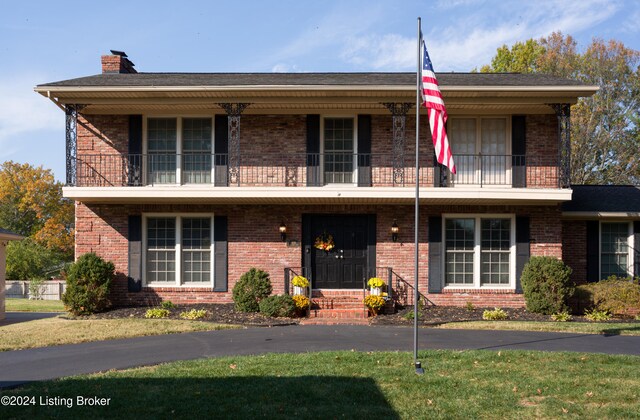 view of front of house with a front yard and a balcony