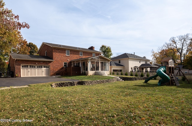 back of house with a garage, a playground, a sunroom, and a lawn