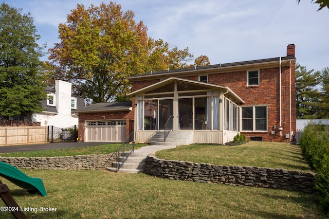 back of house featuring a garage, a lawn, and a sunroom