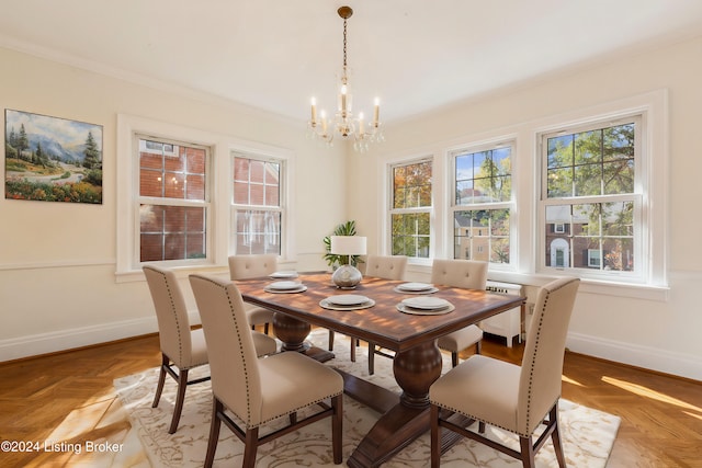 dining space featuring light parquet flooring, ornamental molding, and a chandelier