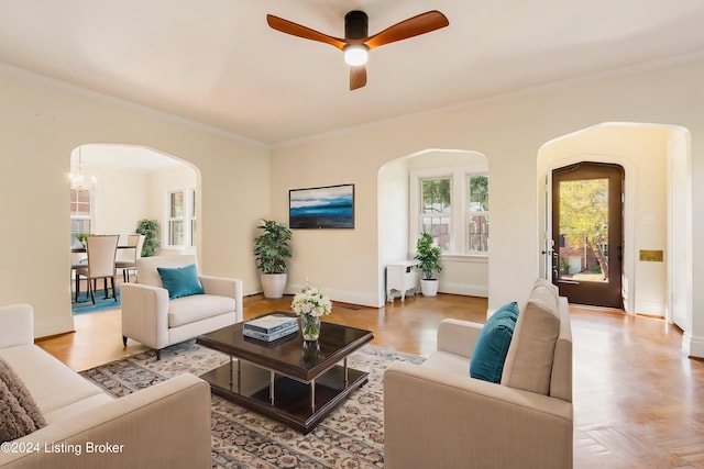 living room featuring ornamental molding, light parquet floors, and ceiling fan with notable chandelier