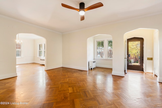 unfurnished room featuring radiator heating unit, ornamental molding, ceiling fan with notable chandelier, and parquet floors