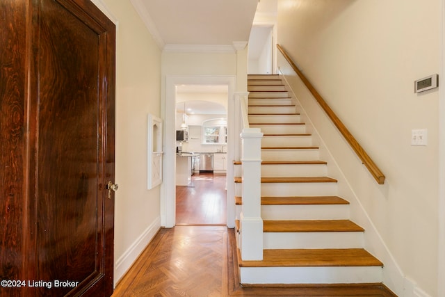 staircase with parquet flooring and crown molding