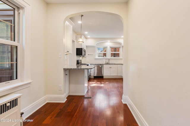 interior space featuring white cabinets, hanging light fixtures, dark hardwood / wood-style flooring, light stone countertops, and stainless steel appliances