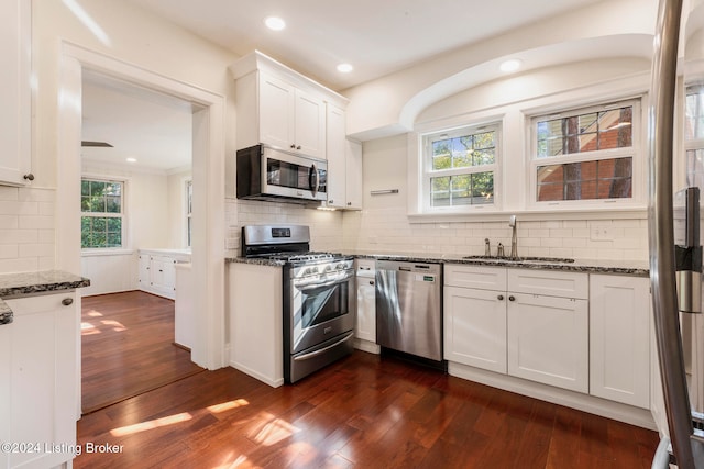 kitchen featuring white cabinets, dark stone countertops, stainless steel appliances, and dark wood-type flooring