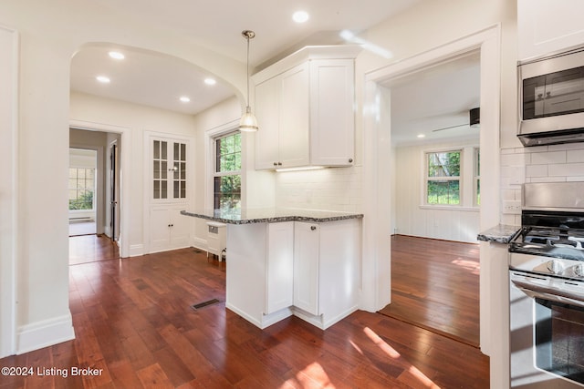 kitchen with white cabinets, stainless steel appliances, dark hardwood / wood-style floors, and dark stone counters