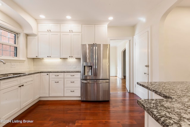 kitchen with sink, stainless steel fridge with ice dispenser, dark hardwood / wood-style floors, and dark stone countertops