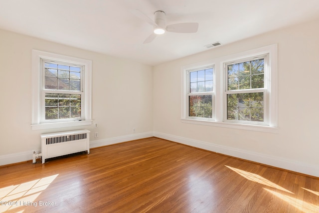 spare room featuring radiator heating unit, hardwood / wood-style flooring, plenty of natural light, and ceiling fan