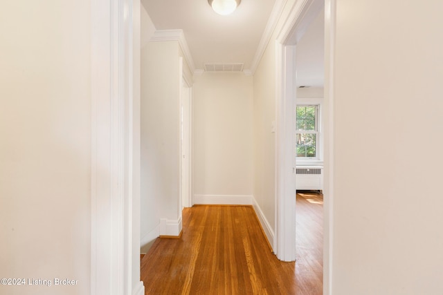 hallway featuring ornamental molding, hardwood / wood-style flooring, and radiator heating unit