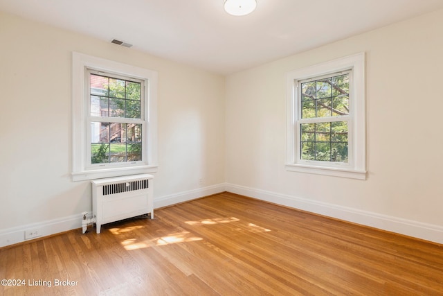 spare room featuring radiator, a wealth of natural light, and light wood-type flooring