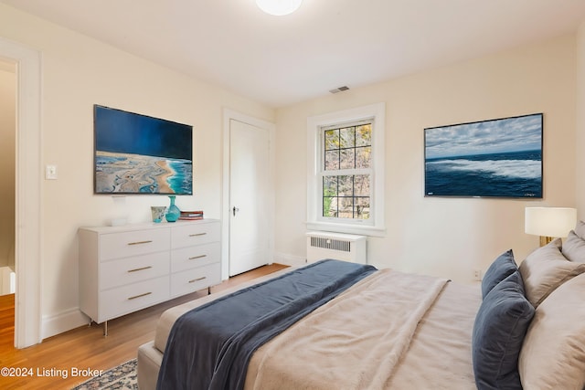 bedroom featuring radiator heating unit and light hardwood / wood-style floors