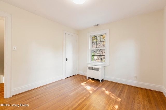 unfurnished bedroom with light hardwood / wood-style flooring and radiator