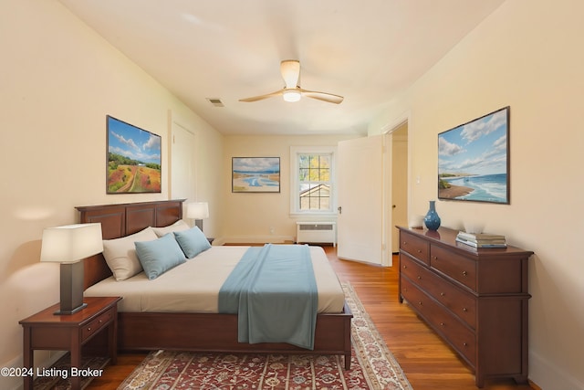 bedroom with hardwood / wood-style floors, radiator heating unit, and ceiling fan