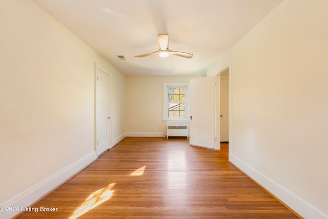 spare room featuring hardwood / wood-style floors, radiator, and ceiling fan