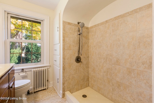 bathroom with tiled shower, toilet, tile patterned flooring, vanity, and radiator heating unit