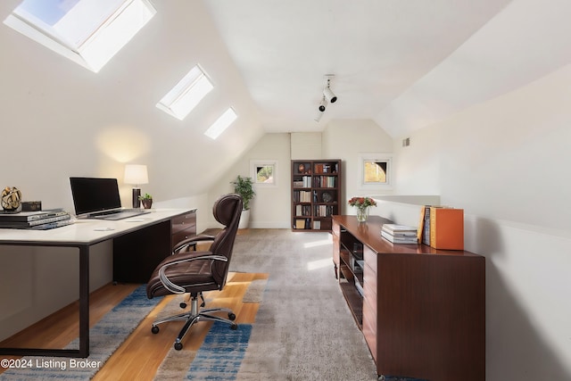 office space featuring lofted ceiling with skylight, wood-type flooring, and rail lighting