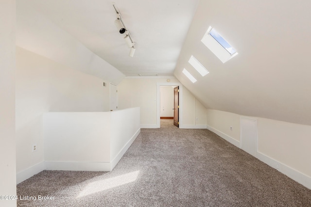 additional living space with lofted ceiling with skylight and carpet flooring