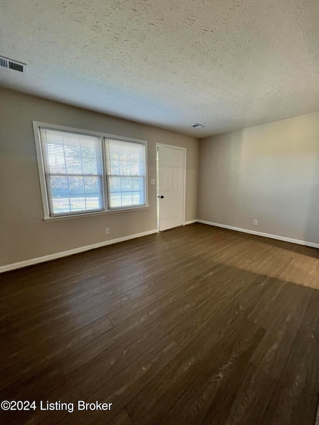 unfurnished room featuring a textured ceiling and dark wood-type flooring