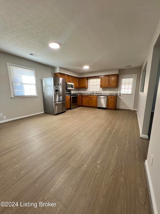 kitchen with light hardwood / wood-style flooring, a textured ceiling, and stainless steel appliances