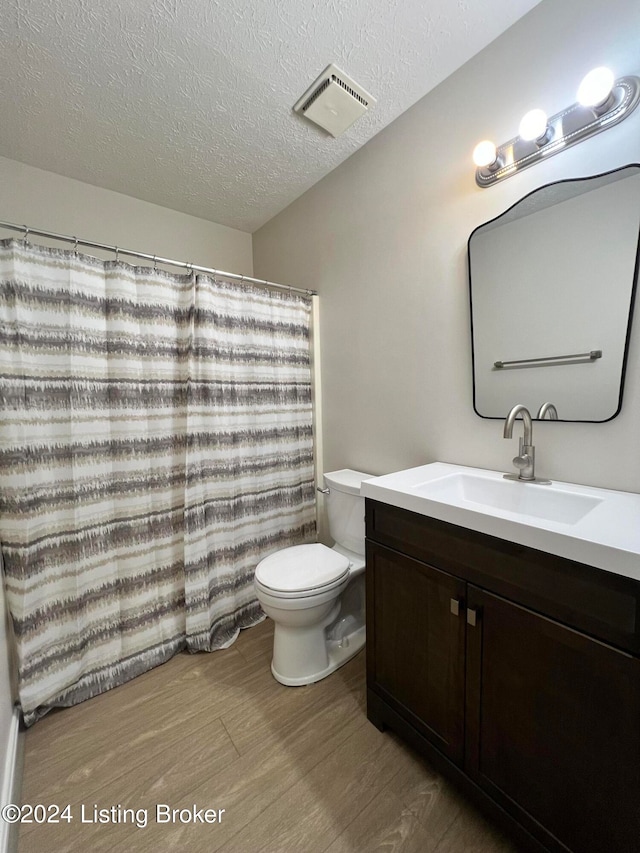 bathroom featuring vanity, toilet, wood-type flooring, and a textured ceiling