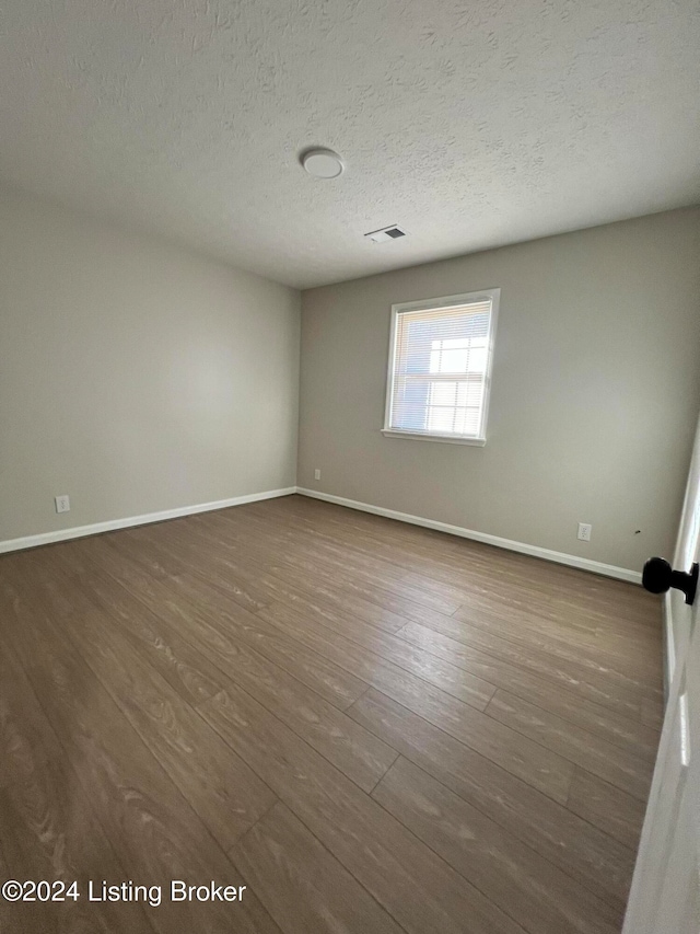 unfurnished room featuring a textured ceiling and dark hardwood / wood-style flooring